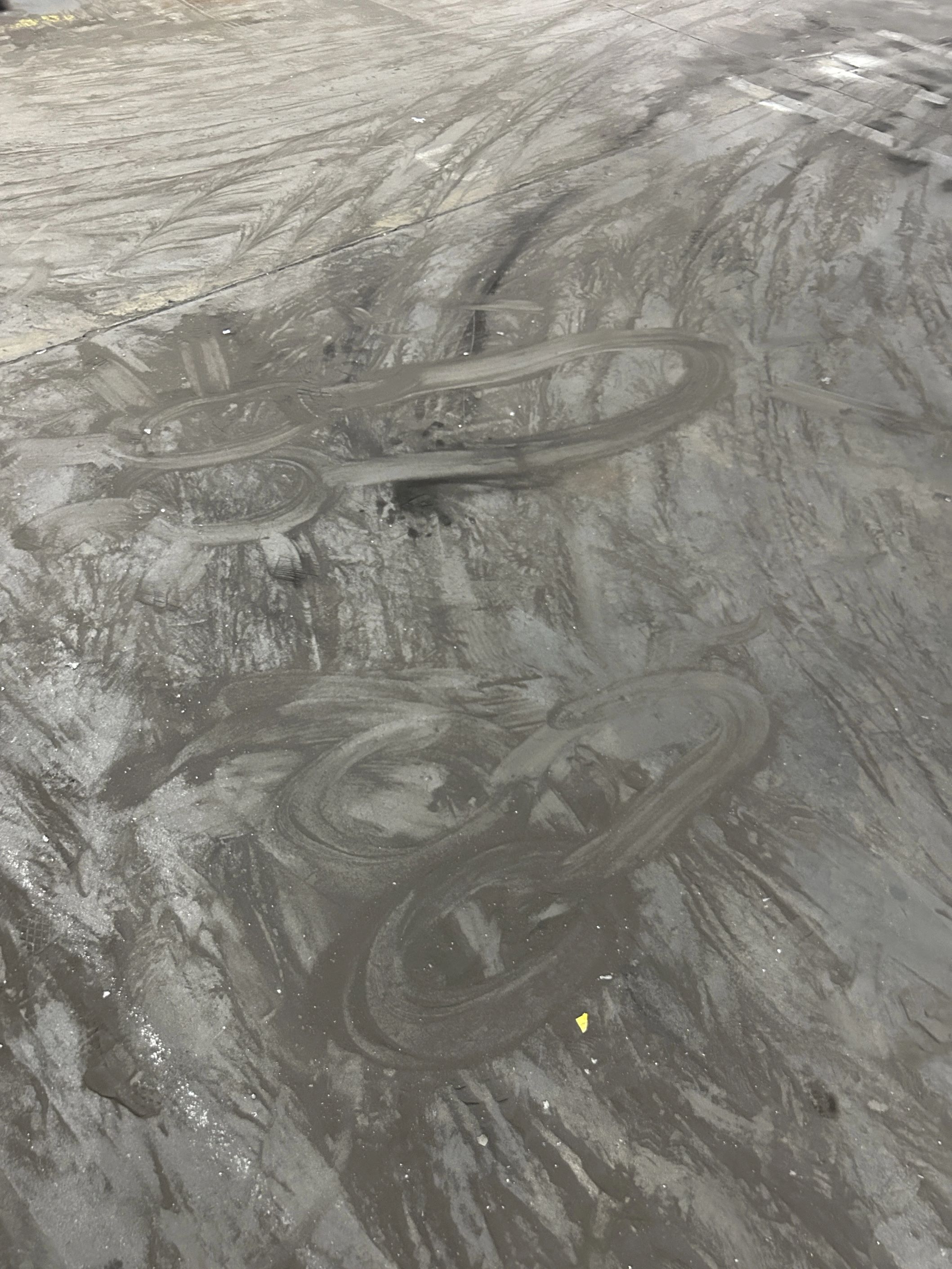 Image of two penises scraped into black dust and dirt on grey concrete.